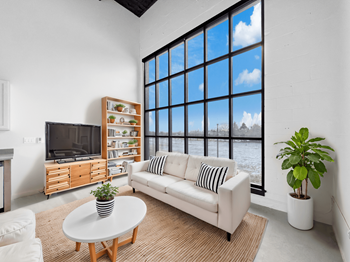 A living room with a white couch, a television, and a large window.